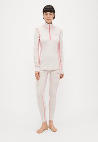 Σετ αθλητικών ρούχων εφαρμοστά σε ανοιχτό ροζ με πιο σκούρες ραφές. Το μακρυμάνικο τοπ έχει φερμουάρ στο ένα τέταρτο, ενώ το παντελόνι είναι μακρύ με λεία υφή.