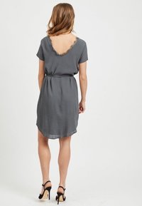 Robes grises courtes avec un dos en V profond bordé de dentelle, manches courtes et taille cintrée, offrant une coupe décontractée et un ourlet fluide.
