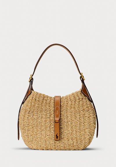 Vävd axelväska i halm med en böjd brun läderrem och knappstängning med en liten djurlogo på vit bakgrund.