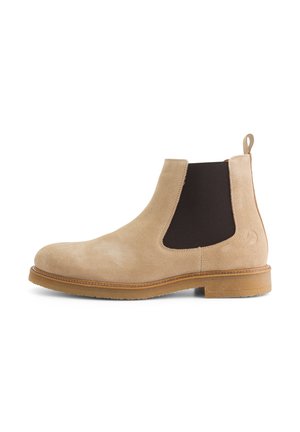 Beige suède Chelsea-boot met elastische zijkanten, ronde neus en een tan rubberen zool. Voorzien van een trekband aan de achterkant voor gemakkelijker aantrekken.