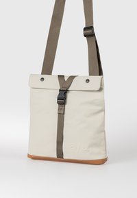 Beige rechteckige Umhängetasche mit braunem verstellbarem Riemen, vorderer Schnallenverschluss, Druckknöpfen und hellbraunem Lederbesatz am Boden.