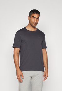 Herre t-shirt med korte ærmer i mørkegrå, lavet af bomuld. Har en rund hals og et lille logo på brystet. Glat tekstur og enkelt design.