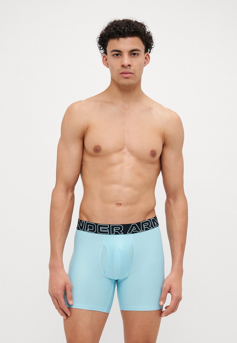 Helle blaue Boxershorts mit einem schwarzen Bund, der in fetter, weißer Schrift "UNDER ARMOUR" trägt. Glattes Material und enganliegendes Design.