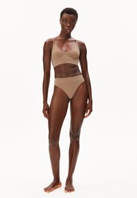 Beiger nahtloser BH und hochtaillierter Bikinihose, weiche Textur, dünne Träger, minimalistisches Design, präsentiert an einem Modell vor einem schlichten Hintergrund.