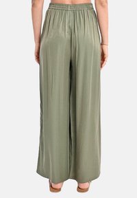 Pantaloni larghi in tessuto verde oliva, dalla texture liscia, con vita elastica, design plissettato, vestibilità casual e taglio alla caviglia.