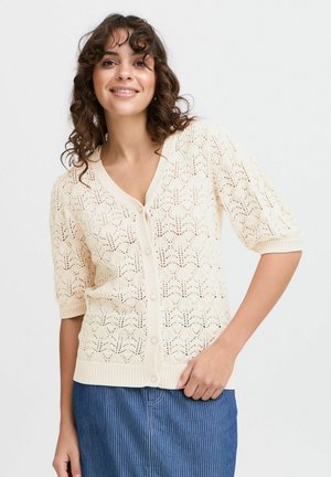 Cardigan en tricot beige avec un col en V, motif en dentelle, manches courtes et fermeture à boutons ; accents en tricot côtelé au niveau des poignets et de l'ourlet.