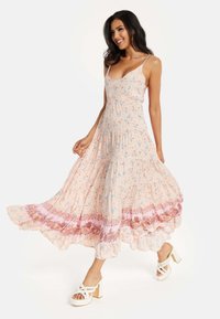 Floral maxi dress in soft pink with blue accents, spaghetti straps, pleated texture, and a ruffled hem featuring intricate embroidery details.
