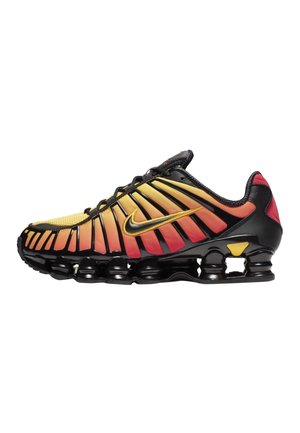 Chaussure de sport dégradée noir et orange avec un swoosh jaune, semelle noire avec amortisseurs visibles et lacets noirs, vue de côté.