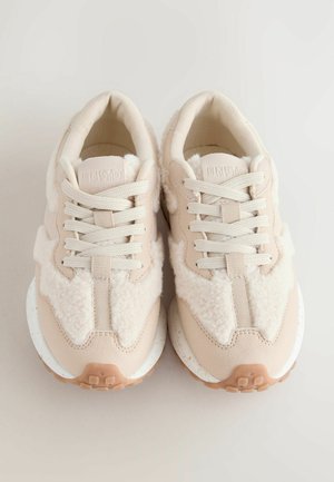 Sneaker beige caratterizzate da un mix di pile testurizzato e suede liscio. Suole spesse bianche macchiate e lacci piatti coordinati completano il design.