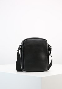Black leather crossbody bag, rectangular shape, zip closure, adjustable strap, smooth texture, minimal design, silver hardware accents.