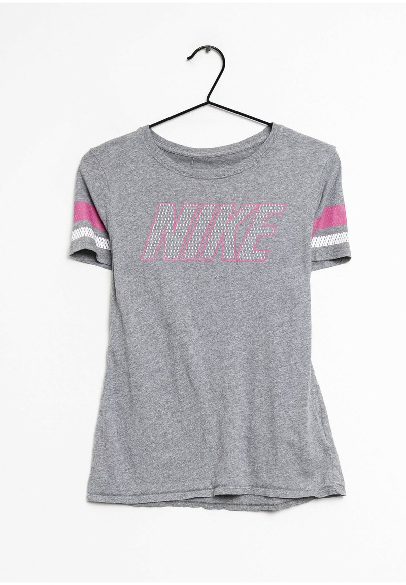 T-shirt en coton gris à manches courtes, avec un grand logo "NIKE" rose et des accents rayés en rose et blanc sur les manches. Accroché à un crochet noir.