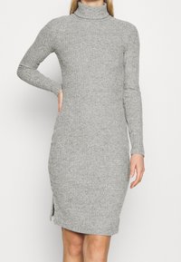 Abito grigio a collo alto a costine con maniche lunghe, dettaglio con spacco laterale e design aderente. La morbida texture a maglia migliora il comfort.