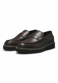 Bruine leren loafers met een gestructureerde bovenkant, voorzien van een penny-slot detail, gestikte accenten en een robuuste zwarte rubberen zool.