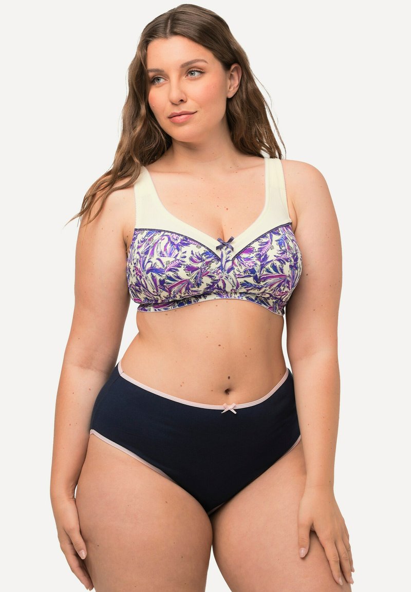 Il reggiseno presenta una stampa floreale in viola e crema, con spalline larghe e un piccolo fiocco decorativo. Gli slip a vita alta di colore navy completano l'insieme.