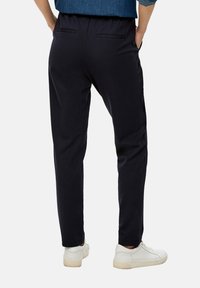 Marine joggers met zijzakken, elastische tailleband en taps toelopende pijpen, gecombineerd met witte sneakers. Soepele stofstructuur.