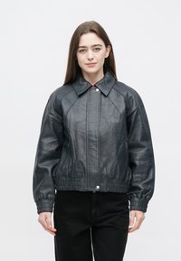 Donkergrijze leren bomberjack met kraag, geribbelde manchetten en een getailleerde taille. Voorzien van een ritssluiting aan de voorkant en zijzakken. Gladde textuur.