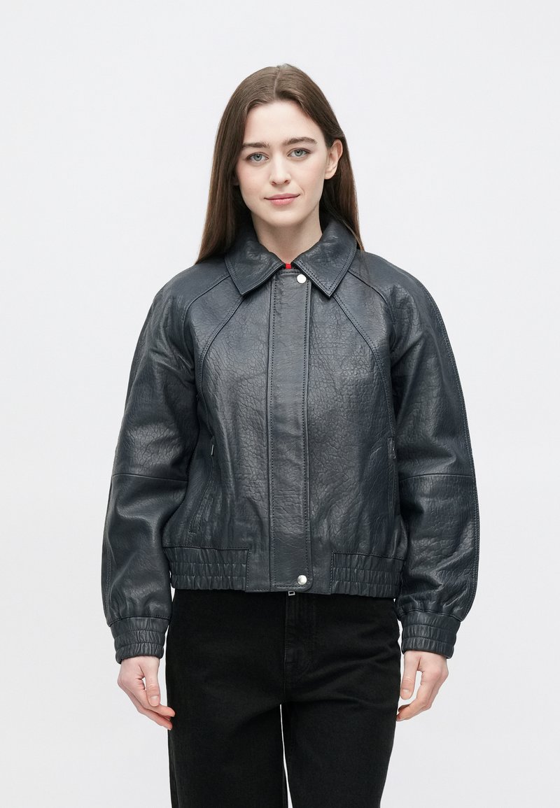 Donkergrijze leren bomberjack met kraag, geribbelde manchetten en een getailleerde taille. Voorzien van een ritssluiting aan de voorkant en zijzakken. Gladde textuur.