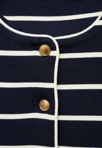 Morski prugasti materijal s horizontalnim bijelim prugama; ima okrugli izrez, zlatne gumbe i rebrastu teksturu.