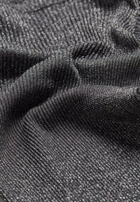 Svart ribbad tyg med små silverglittertrådar som skapar en glittrande, strukturerad yta med mjuka veck.