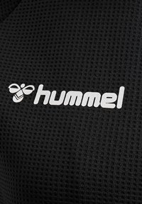 Zwarte mesh sportshirt met een gestructureerd oppervlak. Voorzien van een wit "hummel" logo en een bij-embleem. Zacht materiaal voor comfort.