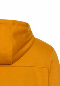 Sweatshirt jaune avec une grande capuche, texture lisse et couture visible le long des épaules. Le tissu semble doux et décontracté.