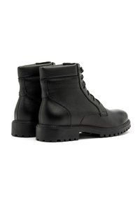 Czarne skórzane botki za kostkę z solidną podeszwą, sznurowanym przodem i gładkim wykończeniem. Posiadają wyściełany kołnierz i boczne szwy.