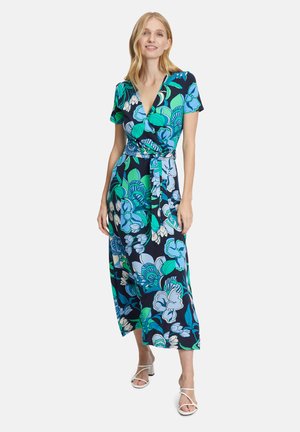 Robe portefeuille florale avec une base bleu marine ornée de motifs floraux verts et bleus, des manches courtes, une taille nouée et une longueur midi.