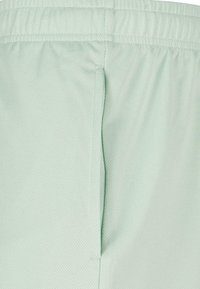 Shorts de sport vert clair texturés avec un tissu en mesh respirant, dotés d'une taille élastique et de détails de couture latérale.