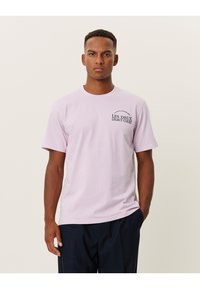 Light purple cotton t-shirt with short sleeves. Features a printed logo design on the left chest area. Straight fit and crew neck.