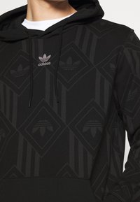 Černá mikina s kapucí s texturovaným vzorem diamantů a logem Adidas, s šňůrkami a klokankovým kapsou.