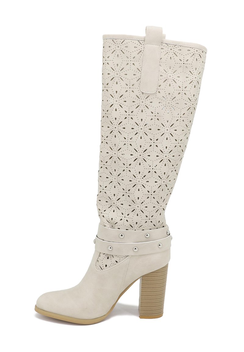Stivale bianco al ginocchio con motivo floreale a laser, texture liscia, tacco a blocco e cinturini con borchie alla caviglia. Presenta un occhiello per il pull-tab nella parte superiore.