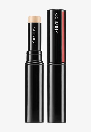 Shiseido foundation stick i ett svart, cylindrisk hylster. Produkten har en hudtonsticka och en stilren design med en röd accent.