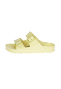 Sandalia amarilla tipo slip-on con dos hebillas ajustables, plantilla texturizada y una suela de goma resistente con un dibujo antideslizante.