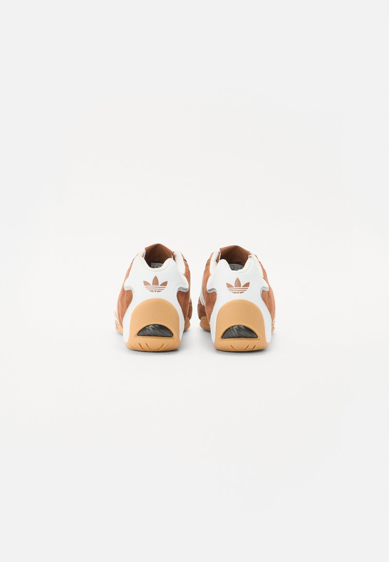 Braune Wildledersneaker mit weißen Akzenten, ausgestattet mit einer Gummisohle und ausgeschnittenen Fersen. Logo hinten in Weiß angezeigt.