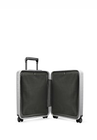 Valise rigide argentée avec une poignée rétractable, quatre roues et deux compartiments doublés en maille. L'intérieur est en tissu foncé.