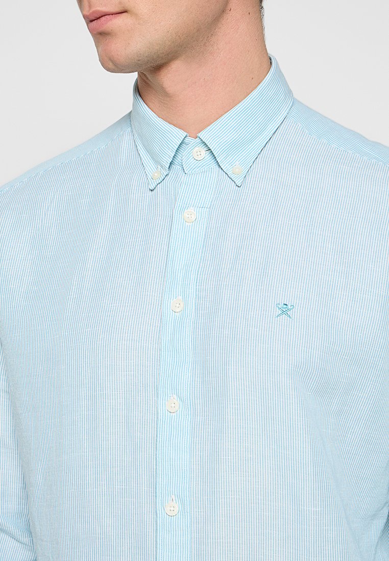Helles blau gestreiftes Button-up-Hemd aus Baumwolle. Verfügt über einen Kragen, weiße Knöpfe und ein kleines gesticktes Logo auf der Brust.