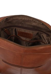 Interno di una borsa in pelle marrone con cerniera. Presenta una fodera marrone scuro, una piccola tasca con zip e vari scomparti per l'organizzazione.