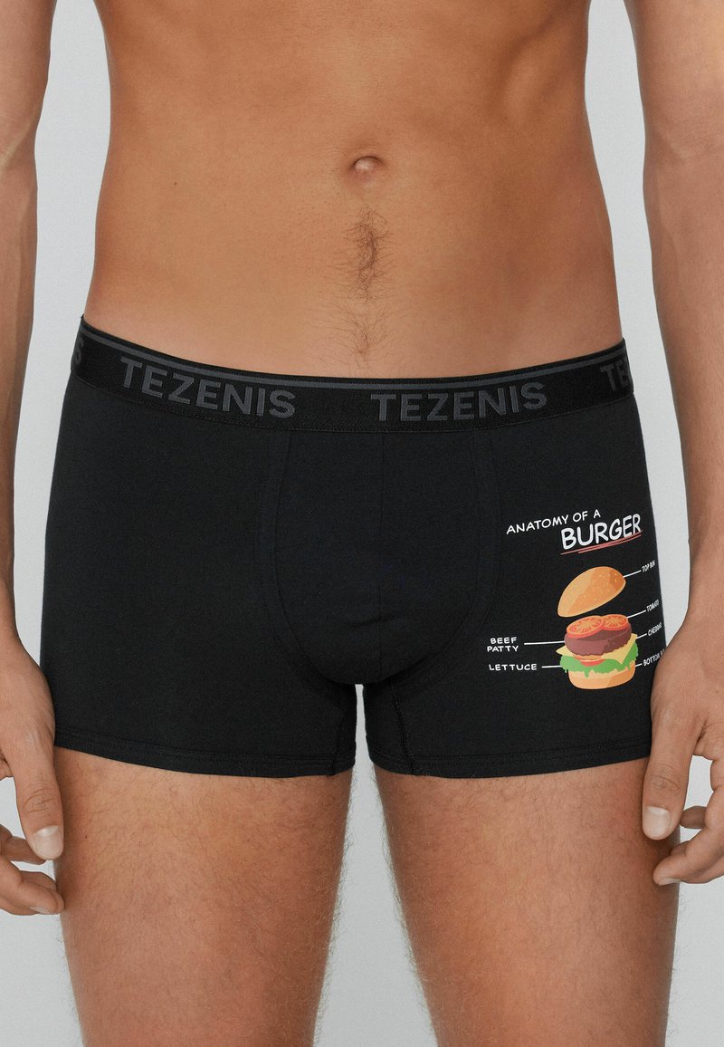 Boxers negros con la gráfica "Anatomía de una Hamburguesa" que presenta una ilustración de hamburguesa y etiquetas de ingredientes. Material de algodón suave con cinturilla elástica.