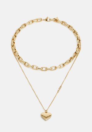 Gold-tone necklace featuring a chunky chain with smooth links, paired with a delicate chain holding a heart-shaped pendant with stone accents.