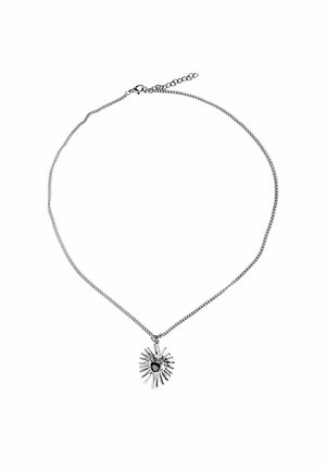 Zilveren ketting met een asymmetrische zonnestraalhanger met een kleine donkere centrale steen op een witte achtergrond.