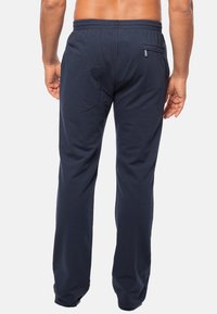 Marineblauwe trainingsbroek van zacht materiaal, met een elastische tailleband, rechte pijpen en een ritszak aan de achterkant.