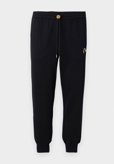 Pantalons de jogging noirs en tissu doux. Taille élastique avec cordon de serrage, accents dorés et revers élastiques aux chevilles. Design minimaliste.