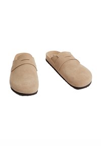 Beige suède instap schoenen met een brede band over de bovenkant en een gestructureerd oppervlak. Donkere rubberen zool voor grip. Gladde binnenvoering.