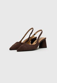 Scarpe slingback in suede marrone con punta affusolata, tacco spesso a blocco e una fascia per una vestibilità sicura. La soletta interna mostra il logo del brand.
