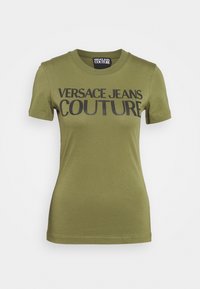 Olivově zelené tričko vyrobené z měkké bavlny s krátkými rukávy, s černým potiskem textu "VERSACE JEANS COUTURE" napříč přední částí.