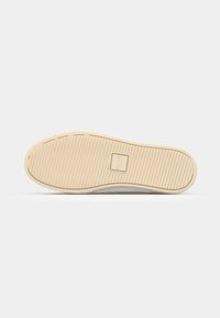 Suola della scarpa in gomma beige, con una superficie testurizzata caratterizzata da scanalature orizzontali e verticali, e un piccolo logo del marchio.