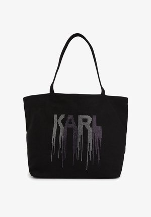 Bolso tote negro con asas largas que presenta la palabra "KARL" en letras de strass con efecto degradado y goteo en la parte delantera.