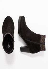 Stivaletti neri in suede con tacco a blocco, dotati di chiusura con zip e un accento in stampa leopardata alla caviglia. Superficie testurizzata.