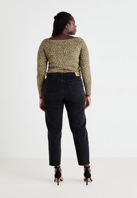 Long-sleeve top with a green and black leopard print, paired with high-waisted black jeans and black stiletto heels.