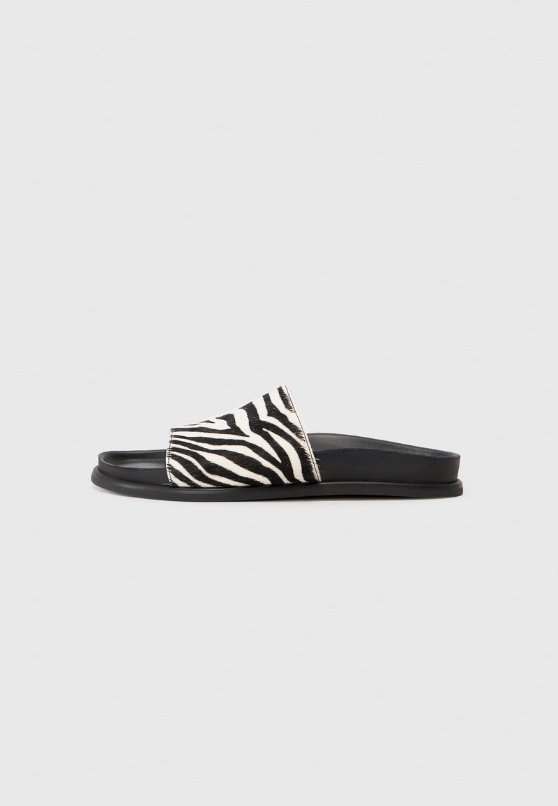 Svart och vit zebratryck slide-sandaler med en mjuk texturerad ovandel och en slät svart gummisula, designade för enkel att ta på.
